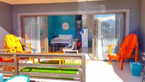 a room with chairs and a bedroom with a bed at Luxury Smart Studio - Sea and Mountain Views - Gordon's Bay in Gordonʼs Bay +1 photo
