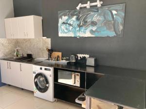 a kitchen with a washing machine and a microwave at Luxury Smart Studio - Sea and Mountain Views - Gordon's Bay in Gordonʼs Bay