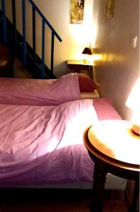 a bed with purple sheets and a table in a room at Gîte de la Grange in Saint-Pardoux