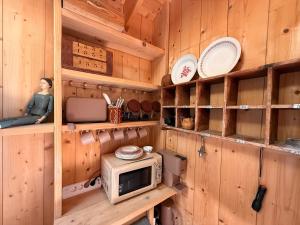 a kitchen with wooden walls and a microwave on a shelf at beachhousebarn in Vendays-Montalivet