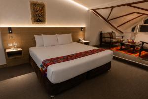 a bedroom with a large bed and a chair at Ecoterra Essentials San Blas in Cusco