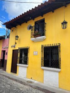 a yellow building with two windows and a balcony at Casa de la Torre in Antigua Guatemala