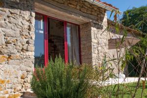 a red door of a stone house with a window at Gîte de la Grange in Saint-Pardoux