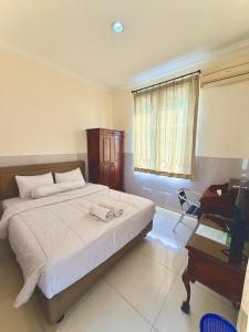 a bedroom with a bed and a desk and a computer at Emerald Inn Karawaci in Dungus
