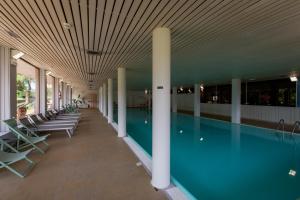 a swimming pool with chairs in a building at Hotel Latemar in Castello di Fiemme