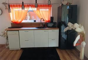 a kitchen with a sink and a window with orange curtains at Oliwa in Gdańsk