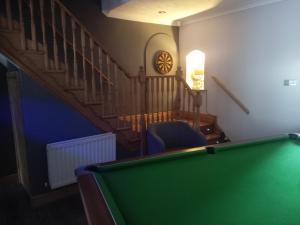 a room with a pool table and a staircase with a clock at Strawberry dream 2 in Newcastle upon Tyne