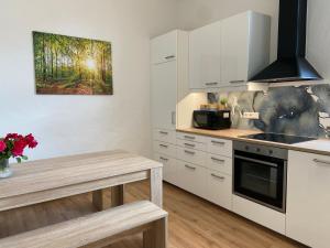a kitchen with white cabinets and a table in it at Kreide & Kissen in Lünebach