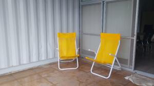 two yellow chairs sitting in a room with blinds at Quincho Paysandu in Arroyo Seco