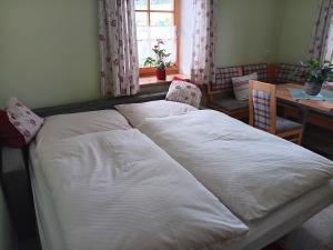 a bed in a room with a table and a window at Biohof Fötschl in Tamsweg