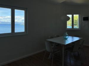 ein Esszimmer mit Tisch und Stühlen und zwei Fenstern in der Unterkunft Apartment Rose in Rogač