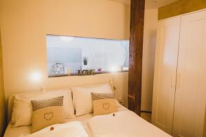 una camera da letto con letto, lenzuola e cuscini bianchi di MOOKI Country Apartment a Villach