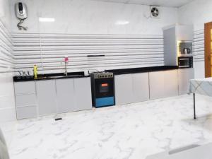 a kitchen with white cabinets and a blue oven at AlZaeem Resort & Hotels in Barka