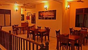 a dining room with wooden tables and chairs at London Palace in Anuradhapura