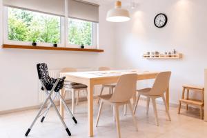 a dining room table with chairs and a clock on the wall at Apartament Bukovy Wisła in Wisła