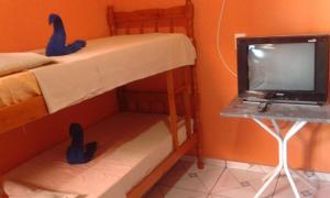 a bedroom with a bunk bed with a tv and a desk at Pousada Ana Raio in Alcobaça