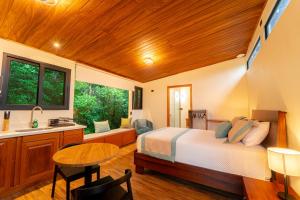 a bedroom with a bed and a table and a sink at Cabañas Hoja Verde in Monteverde Costa Rica