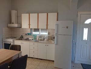 a kitchen with white cabinets and a white refrigerator at Thassos Home in Skala Kallirachis