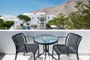 a glass table and two chairs on a balcony at Studio Mary in Perissa