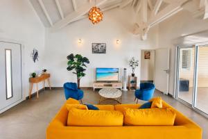 a living room with a yellow couch and blue chairs at Villa Noyanny Piscine Privée Calme in Le Moule