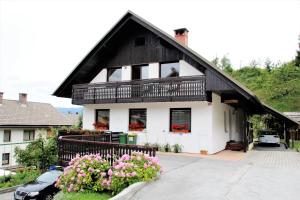 a white house with a black roof and some flowers at 238 Spodnje Gorje in Spodnje Gorje