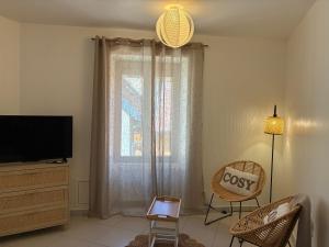 a living room with a tv and a chair at Le 36 du prieuré in Arbois