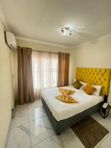 a bedroom with a large bed with a yellow headboard at Indumiso 80 in Newcastle +40 photos