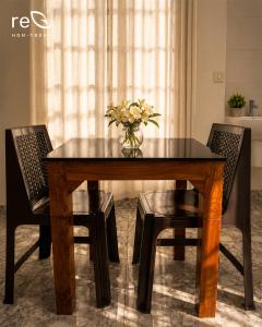 a dining room table with two chairs and a vase with flowers at Re-Leaf Hom-Treat Homestay in Wayanad