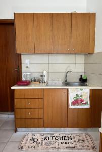 a kitchen with wooden cabinets and a sink at SDROSOS Apartment in Kos +5 photos