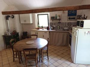 a kitchen with a table and a white refrigerator at Gîte à la campagne in Laborel