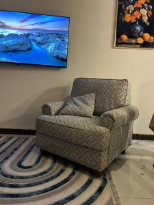a living room with a chair and a painting on the wall at Carmel Residence - كارمل ريزيدنس in Baghdād