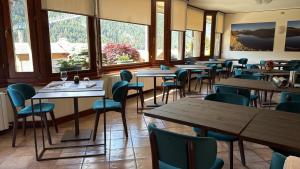 a dining room with tables and chairs and windows at Hotel Sorriso in Ponte di Legno