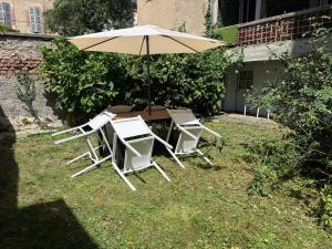 a table and chairs with an umbrella in the grass at F4 Cosy Centre Moulins - 3 chambres lits doubles -idéal Famille & Séjour Pro in Moulins
