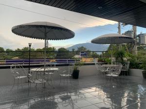 two tables and chairs with umbrellas on a patio at Dream Garden Hotel in Solano