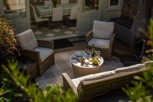 a patio with wicker chairs and a table on a porch at Chy En Glas - By Rowes Retreats in Falmouth