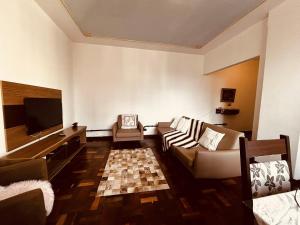 a living room with a couch and a flat screen tv at Confortavel Apartamento na Rua das Flores in Curitiba