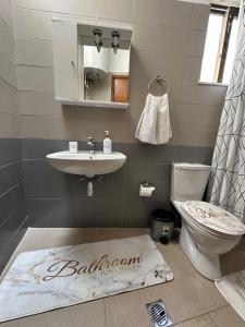 a bathroom with a sink and a toilet and a rug at SDROSOS Apartment in Kos