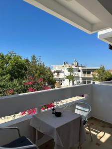 a white table and chairs on a balcony with flowers at SDROSOS Apartment in Kos