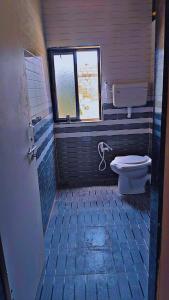 a bathroom with a toilet and a window at Radhe House in Dwarka