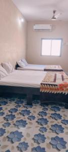 a bedroom with two beds and a rug at Radhe House in Dwarka