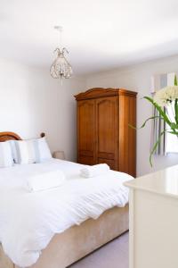 a bedroom with a white bed and a wooden cabinet at Eagles Nest - By Rowes Retreats in Falmouth