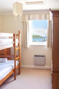 a bedroom with two bunk beds and a window at Eagles Nest - By Rowes Retreats in Falmouth