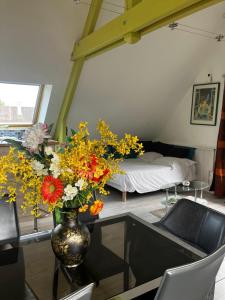 a vase with flowers on a table in a room at L'Ecrin Normand appartement avec jardin comportant 2 lits 2 places et 1 lit 1 place in Cambremer