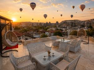 a patio with a table and chairs and hot air balloons at Mai Cappadocia in Göreme
