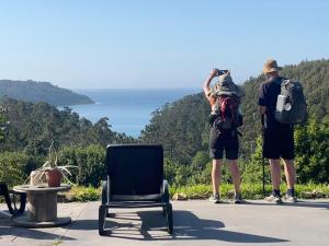 two people taking a picture of the ocean at A Casa da Moucha in Muxia