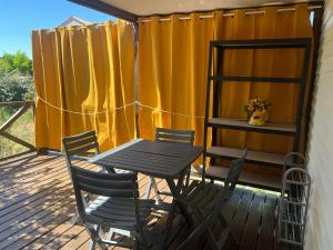 a table and chairs on a deck with a yellow curtain at Mobil home devant un grenadier in Gémenos