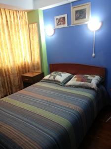 a bedroom with a bed and a blue wall at Hostal Arcangel in Abancay