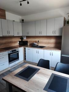 a kitchen with white cabinets and a wooden table at Apartamenty NOVA - BLISKO ENERGYLANDII in Zator