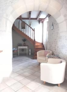 a living room with a staircase and a white chair at laferme de chez Piché in Chérac