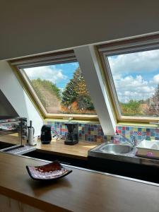 a kitchen with two large windows and a sink at L'Ecrin Normand appartement avec jardin comportant 2 lits 2 places et 1 lit 1 place in Cambremer